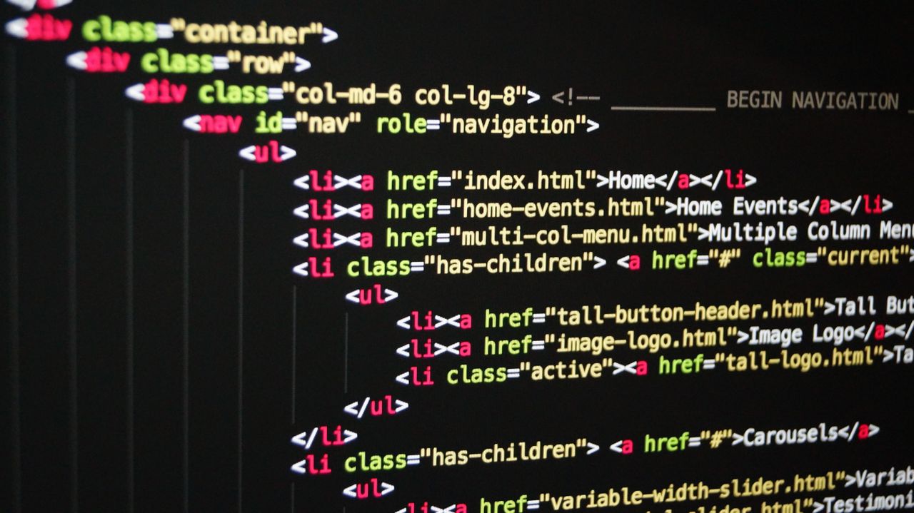 Services Asian male programmer writing code on a computer monitor in an office setting.
