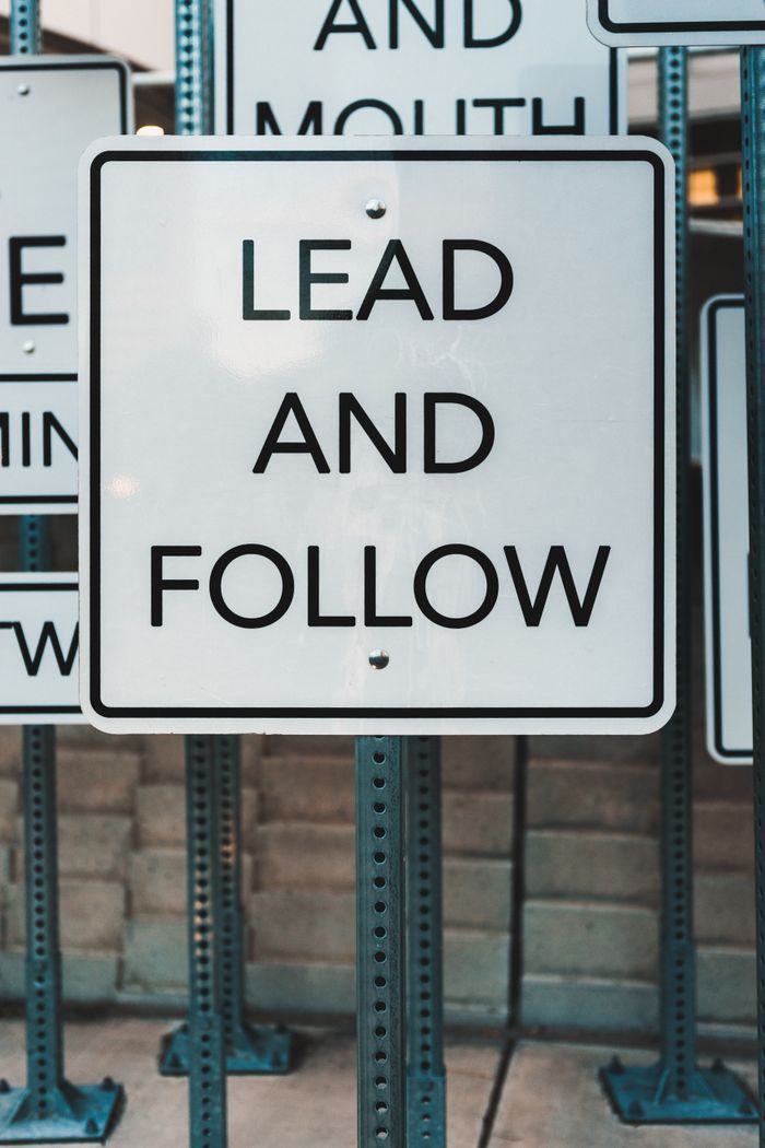 Services Photo of urban signage displaying 'Lead and Follow', emphasizing guidance and navigation.