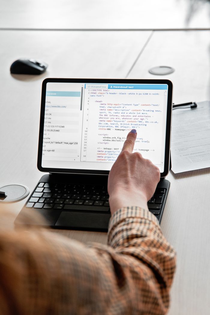 Two individuals discussing code on a laptop, focusing on web development.